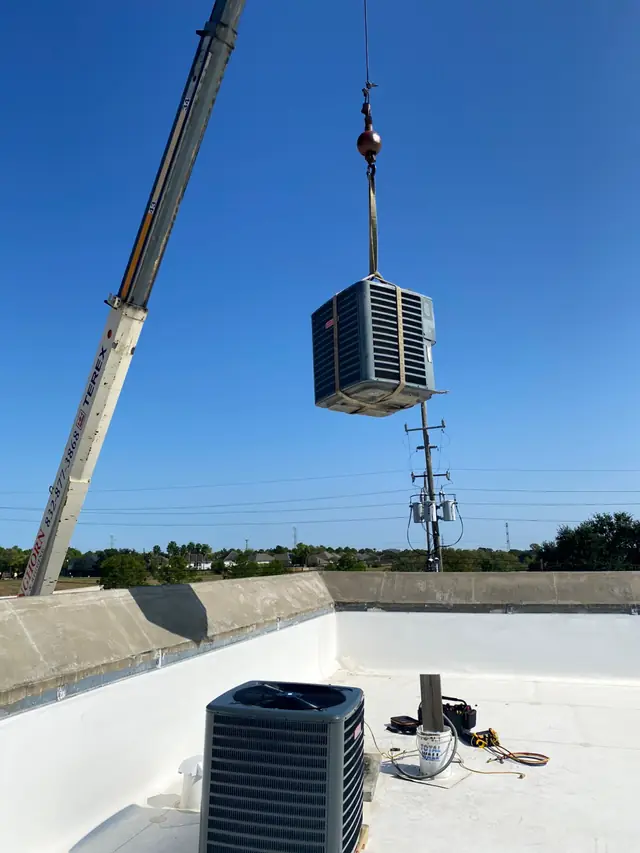 Crane setting a rooftop package unit on a commercial roof